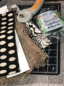 Supplies for a DIY messy bow - rotary cutter, fabric, burlap, and floral wire