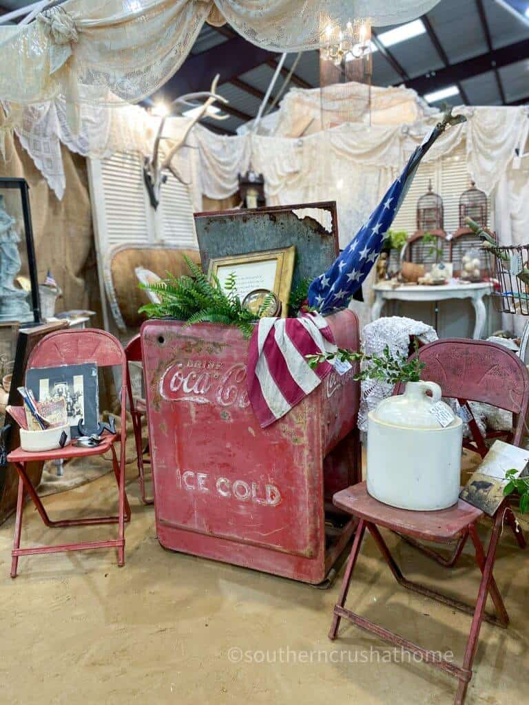vintage coca cola cooler with red metal chairs and american flag