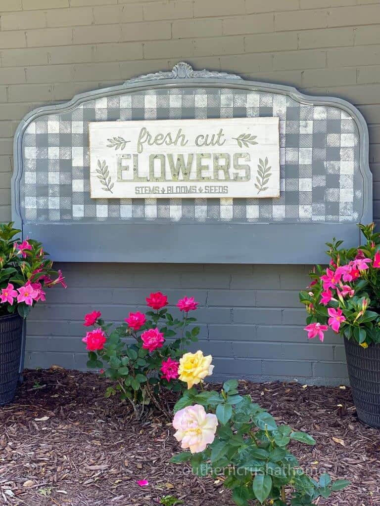 Repurposed Headboard Garden Sign shown outside with flowers