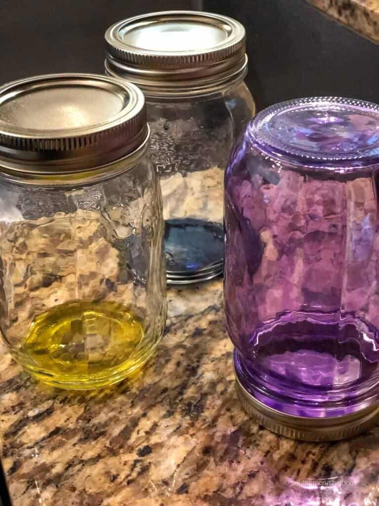 A purple mason jar is upside-down as glass stain coats the sides 