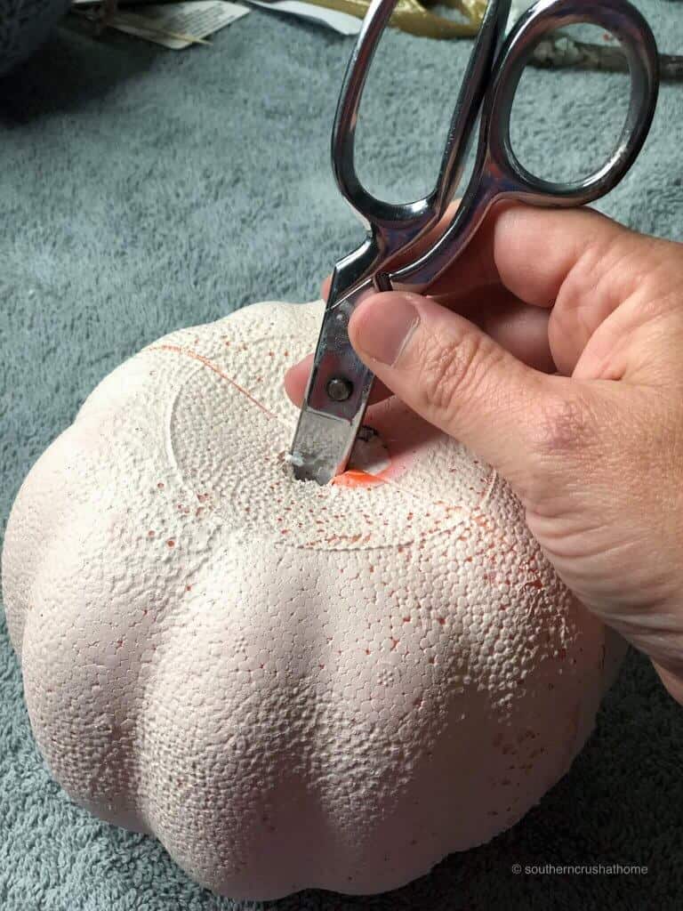 carving a hole into a foam pumpkin