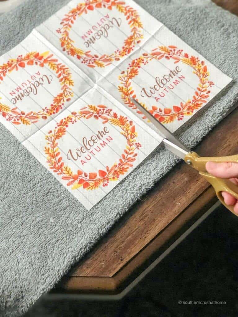 cutting an autumn-themed napkin to use as a candle transfer