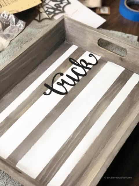 A wooden tray with the word trick on it