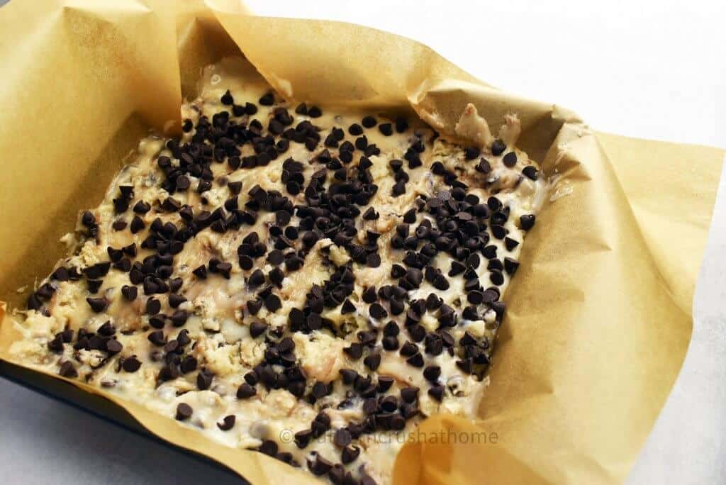 cookie dough fudge spread out in a pan with parchment paper