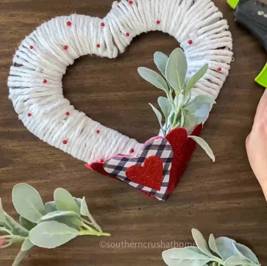 adding greenery to heart pocket of diy wreath