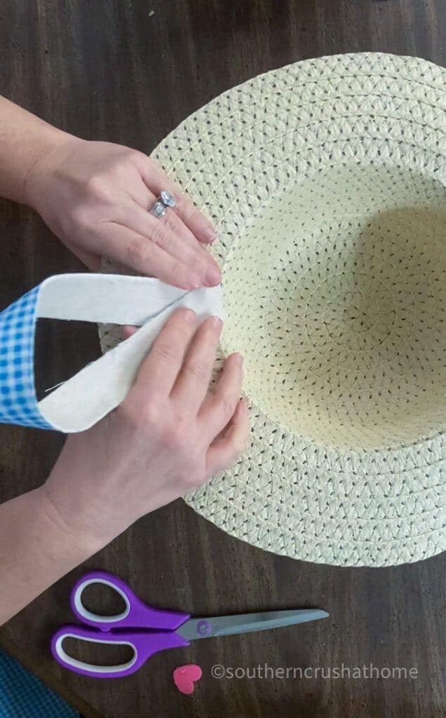 adding ribbon on sun hat for hanging