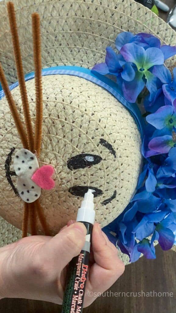 adding white paint to the bunny eyes on sun hat