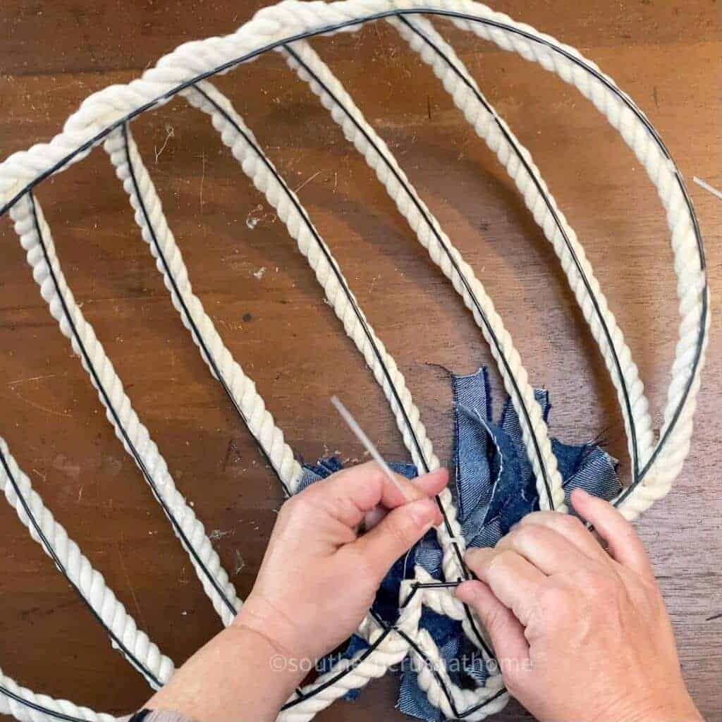 attaching denim bow to pumpkin wreath with zip tie