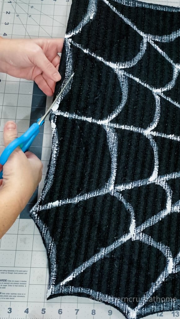 cutting doormat to create spiderweb
