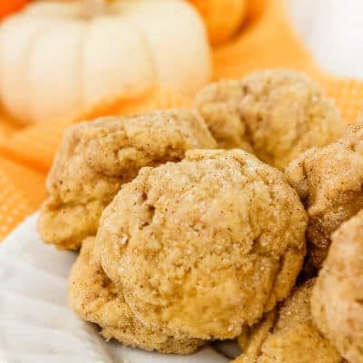 closeup of pumpkin spice cookies stacked with white pumpkin in the background