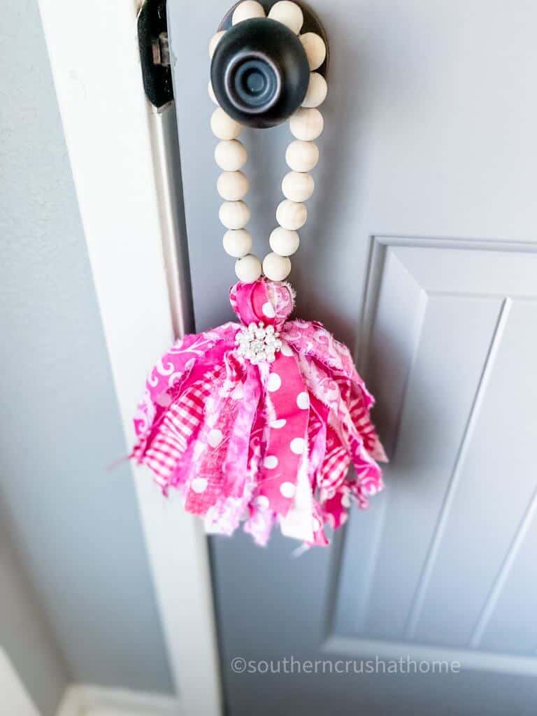 fabric tassel on wood bead garland hanging on door knob