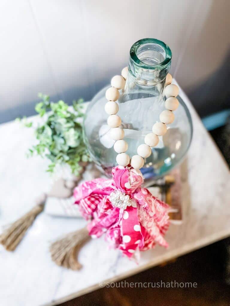 overhead view of wood bead garland hanging on glass bottle