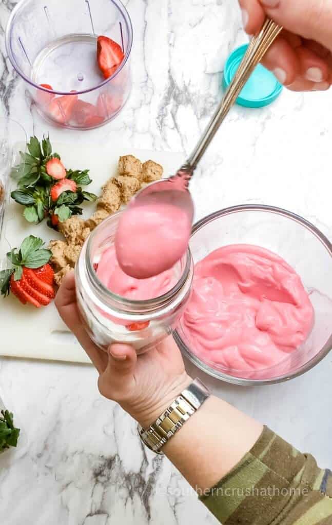 adding strawberry topping to mason jar layer