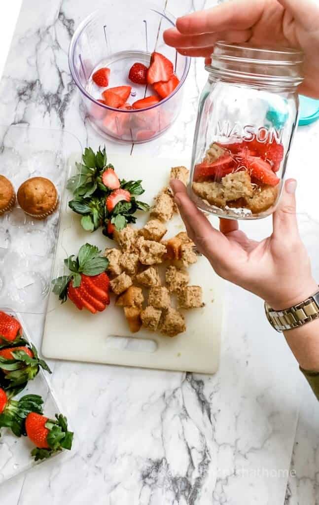 placing strawberries and muffins in mason jar