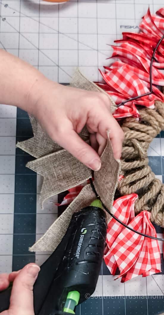 adding burlap ribbon to wreath