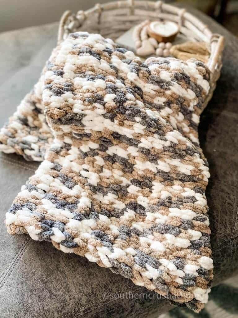 finished chunky yarn blanket draped in basket