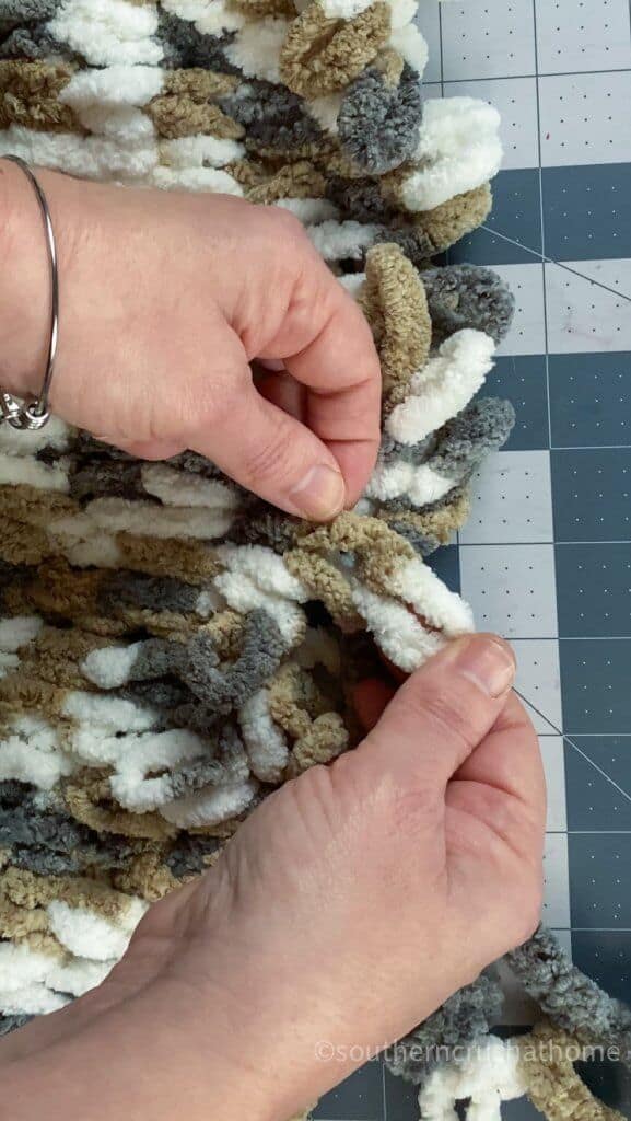 pulling loop through to complete hand knit stitch