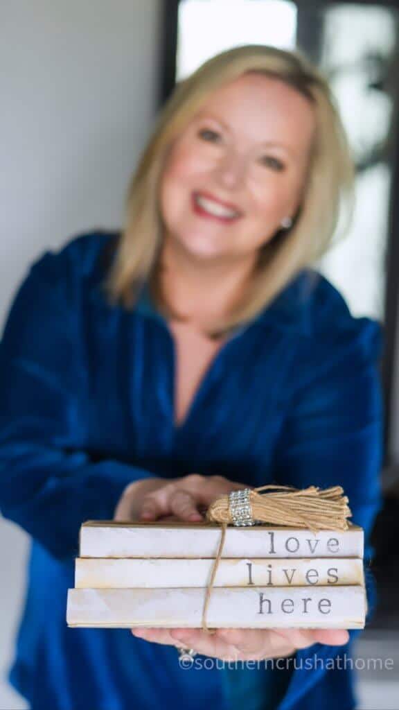 Melanie Ferguson Holding Book Stack Decor