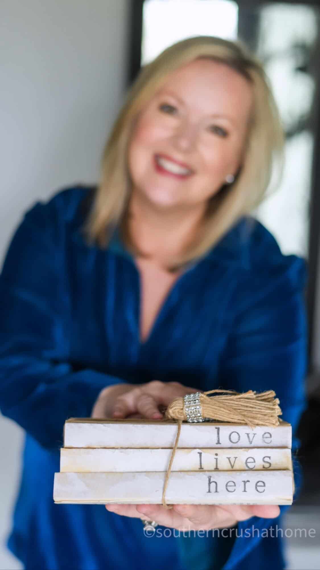 Melanie Ferguson Holding Book Stack Decor