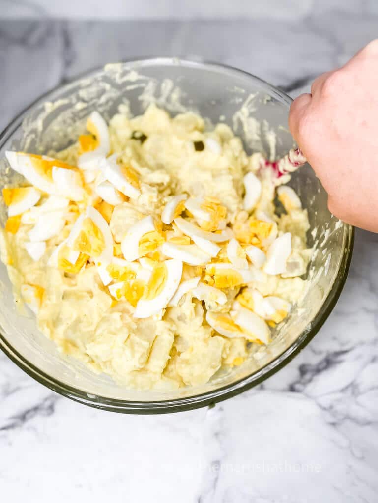 adding eggs to potato salad