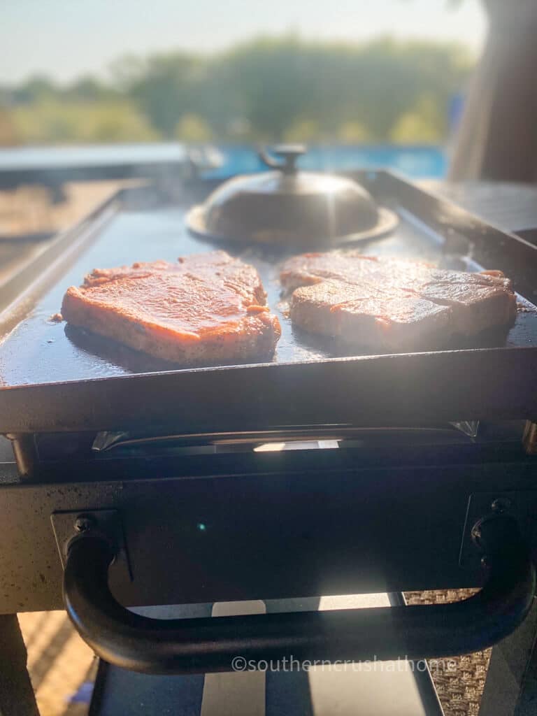 sunset view of steaks cooking on Blackstone griddle