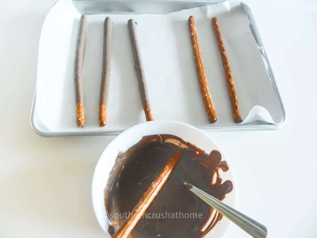 dipping pretzel rods in melted chocolate