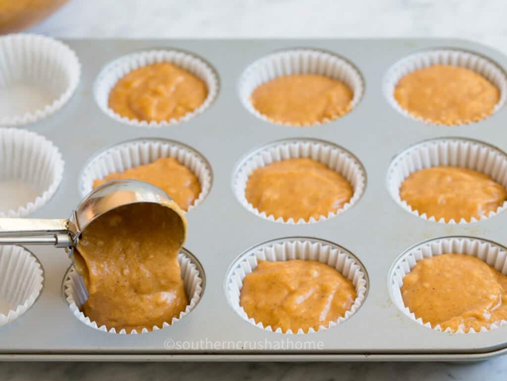 putting pumpkin muffin batter into cupcake holders