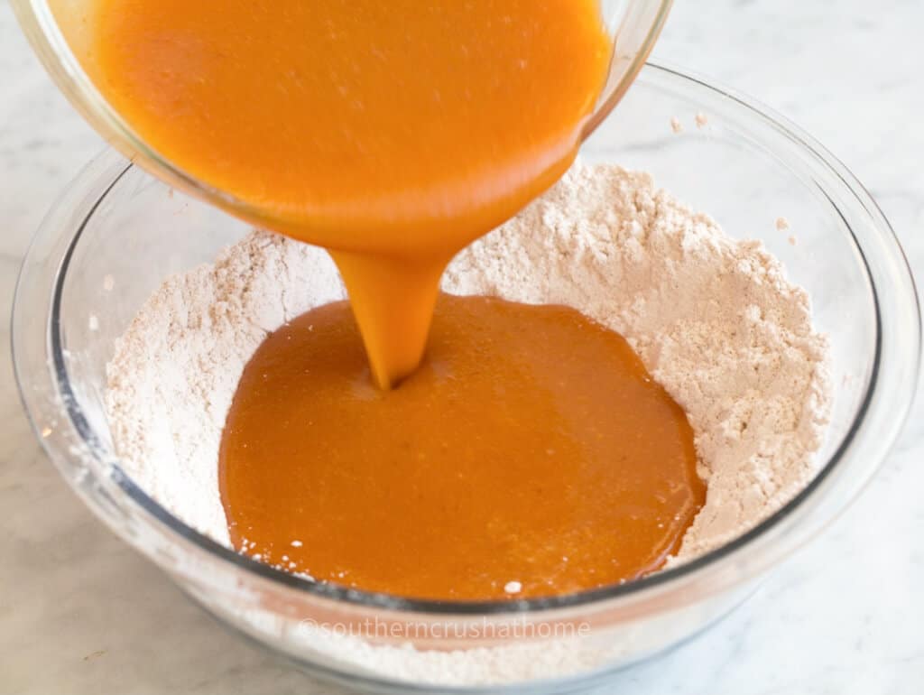 pouring pumpkin puree into dry ingredients