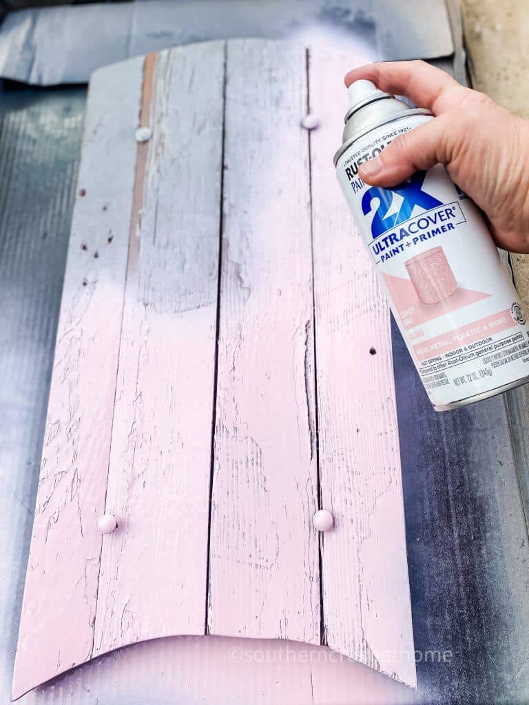 painting pink onto wooden slats of snow sled top
