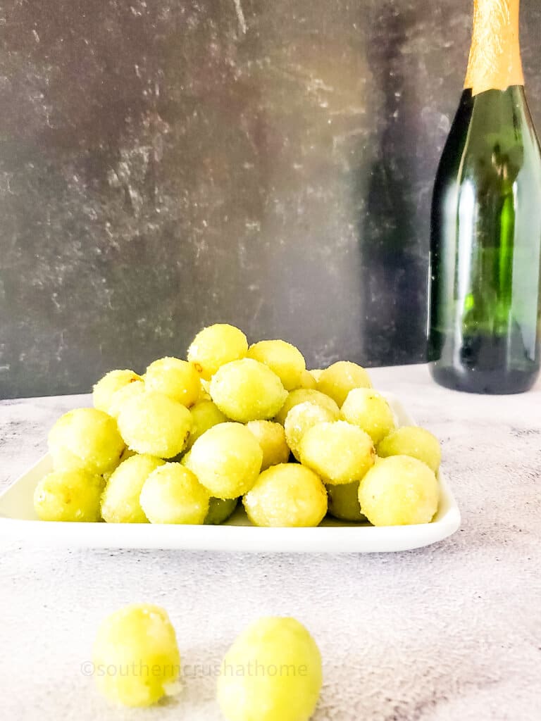 grapes on plate with champagne bottle in background