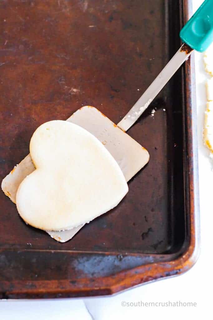 using a spatula to transfer raw cookies to cookie sheet