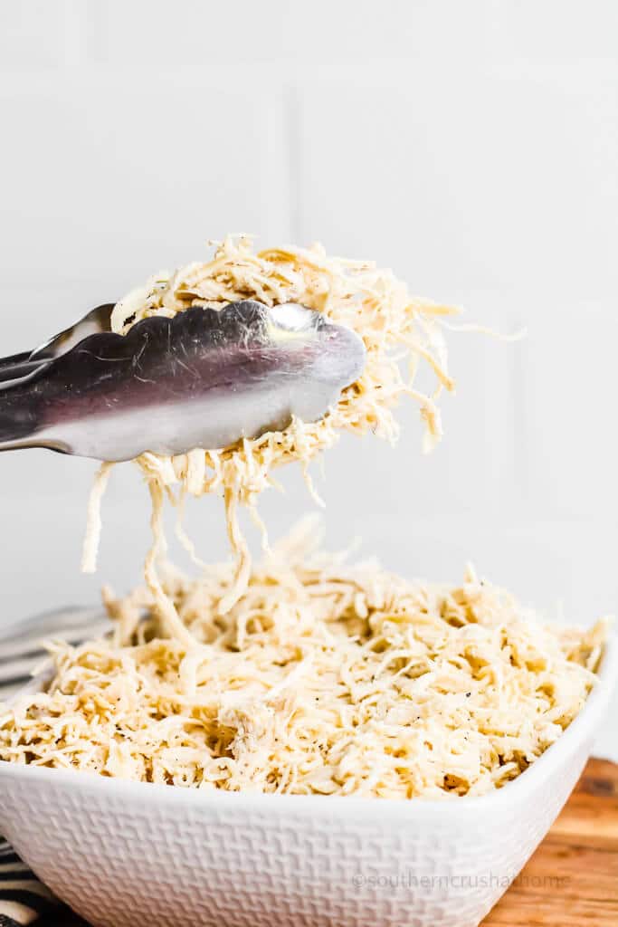 tongs holding up shredded chicken