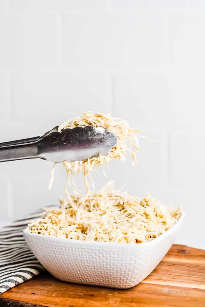 tongs with shredded chicken bowl