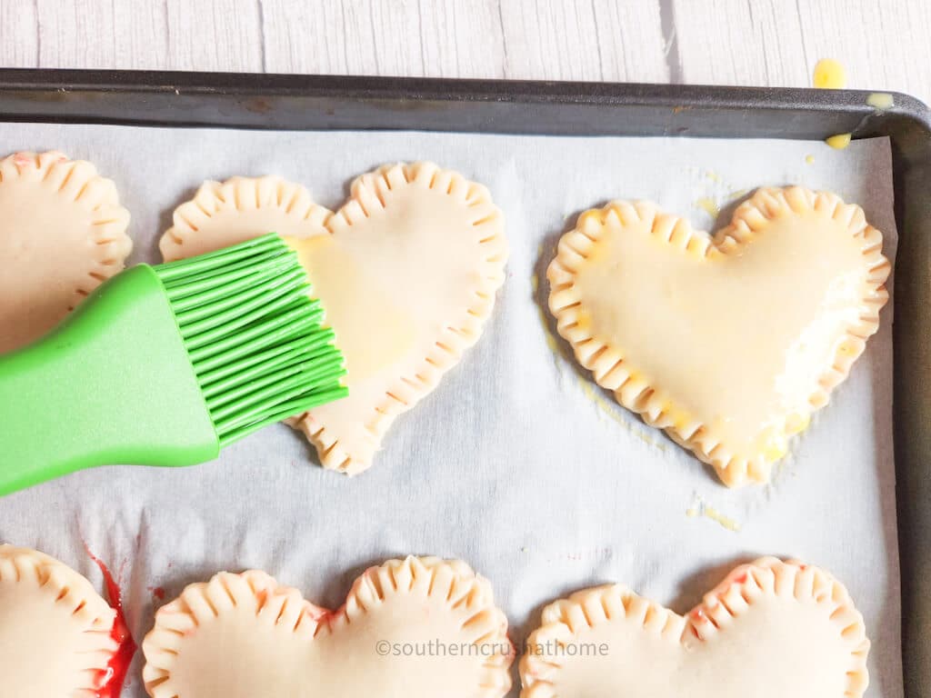 brushing egg whites onto strawberry poptarts