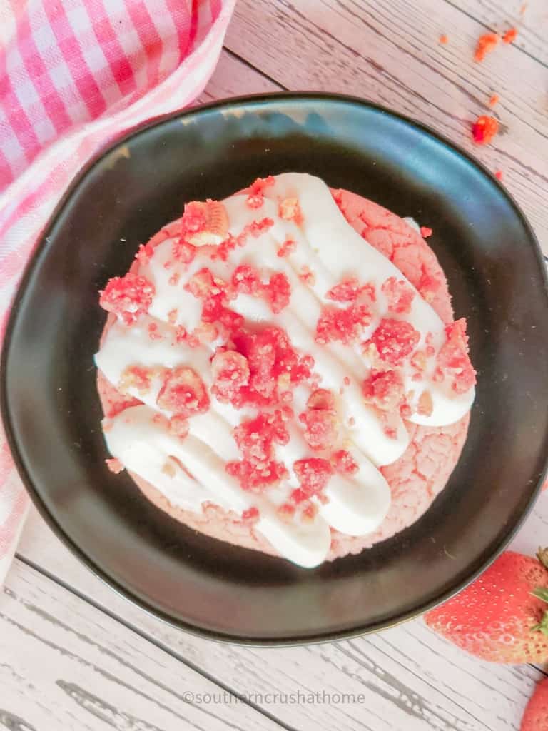 overhead view of copycat crumbl strawberry crunch cookie on black plate