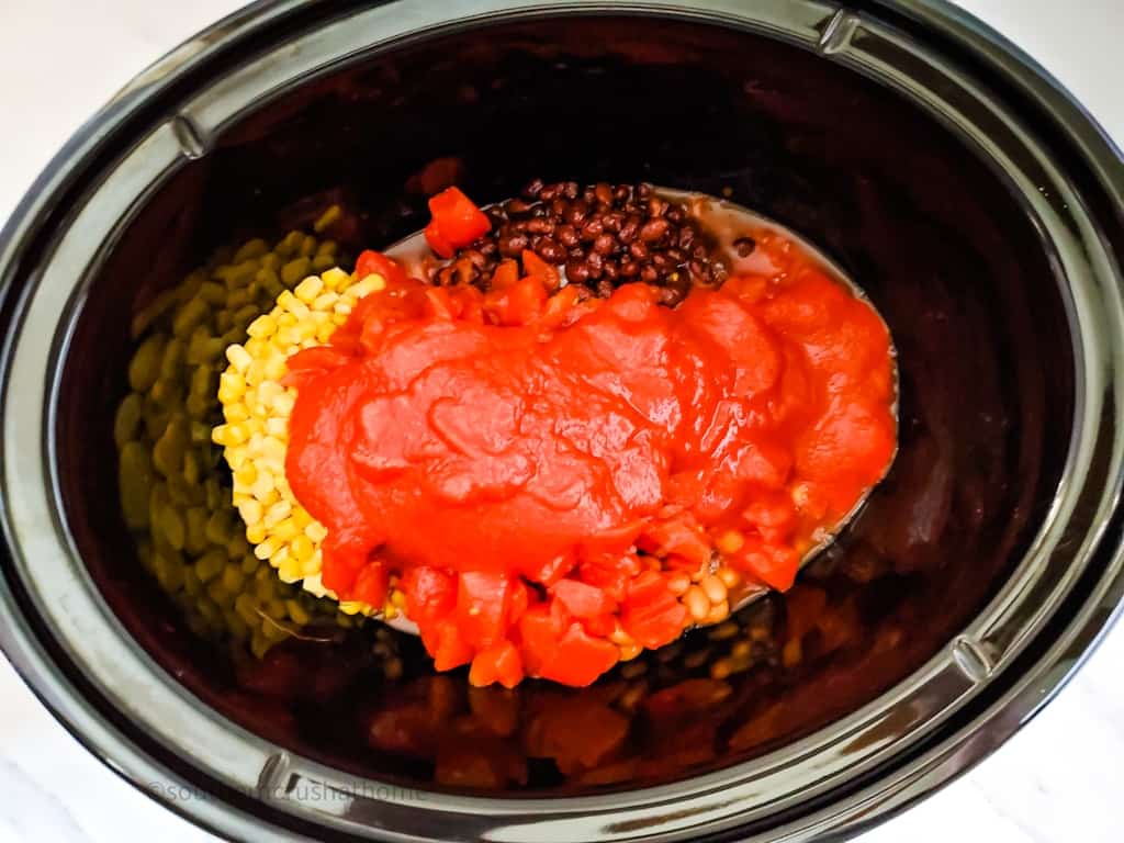tomatoes and tomato sauce on top of beans and corn in crockpot