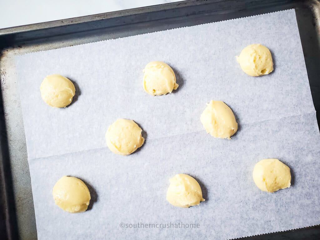 scoops of cookie dough on parchment paper