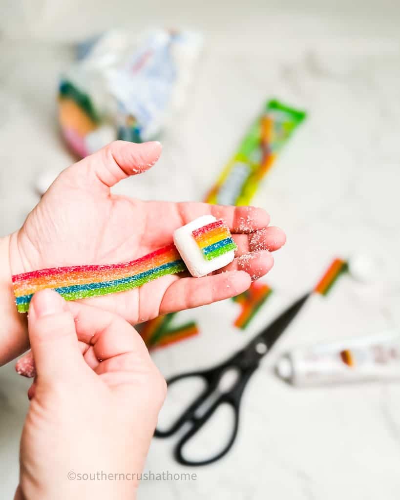 wrapping airhead rainbow berry strip around a marshmallow