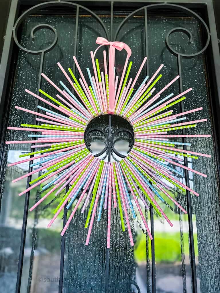 Spring Wreath using Paper Straws hanging on front door with pink ribbon