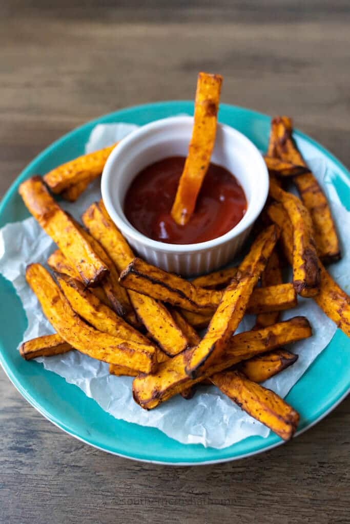 dipping a air fryer sweet potato fry into ketchup