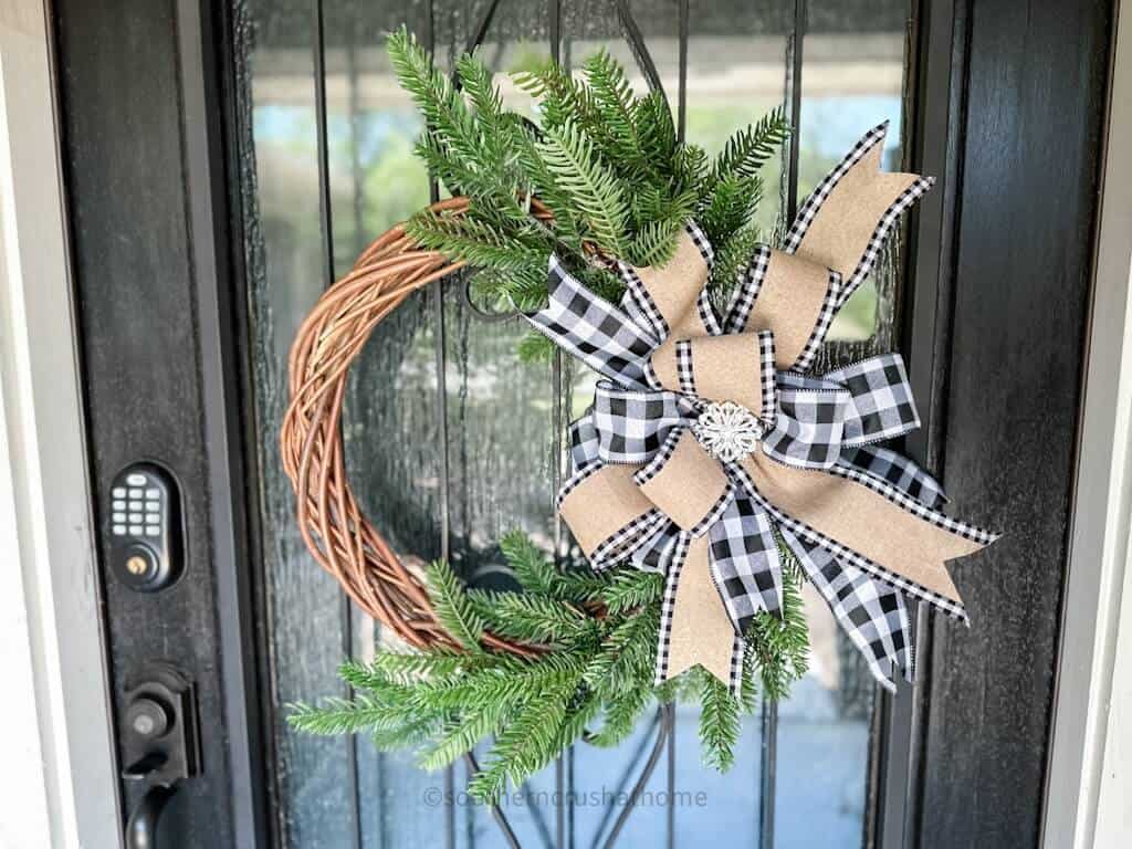 landscape view of finished multi-layer buffalo check bow on a grapevine wreath hanging on my front door