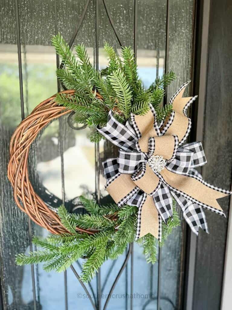 finished multi-layer buffalo check bow on a grapevine wreath hanging on my front door