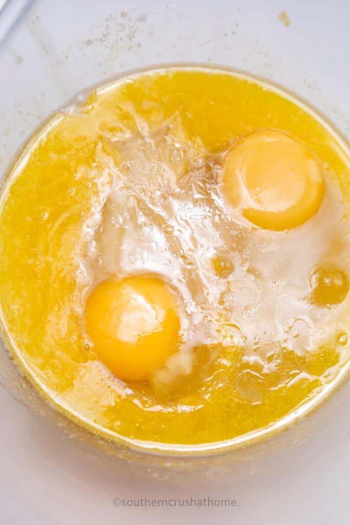 adding eggs and butter to cinnamon roll batter