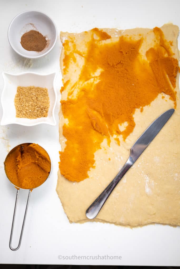 spreading pumpkin puree on to dough