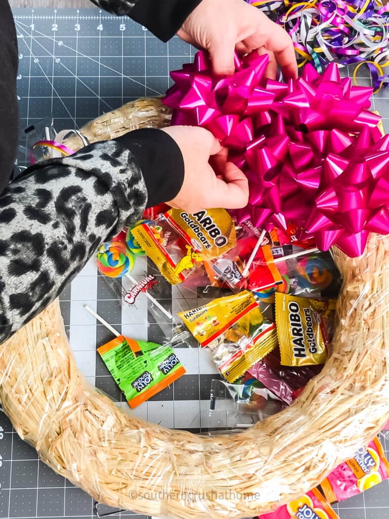 attaching gift bows to halloween wreath with candy