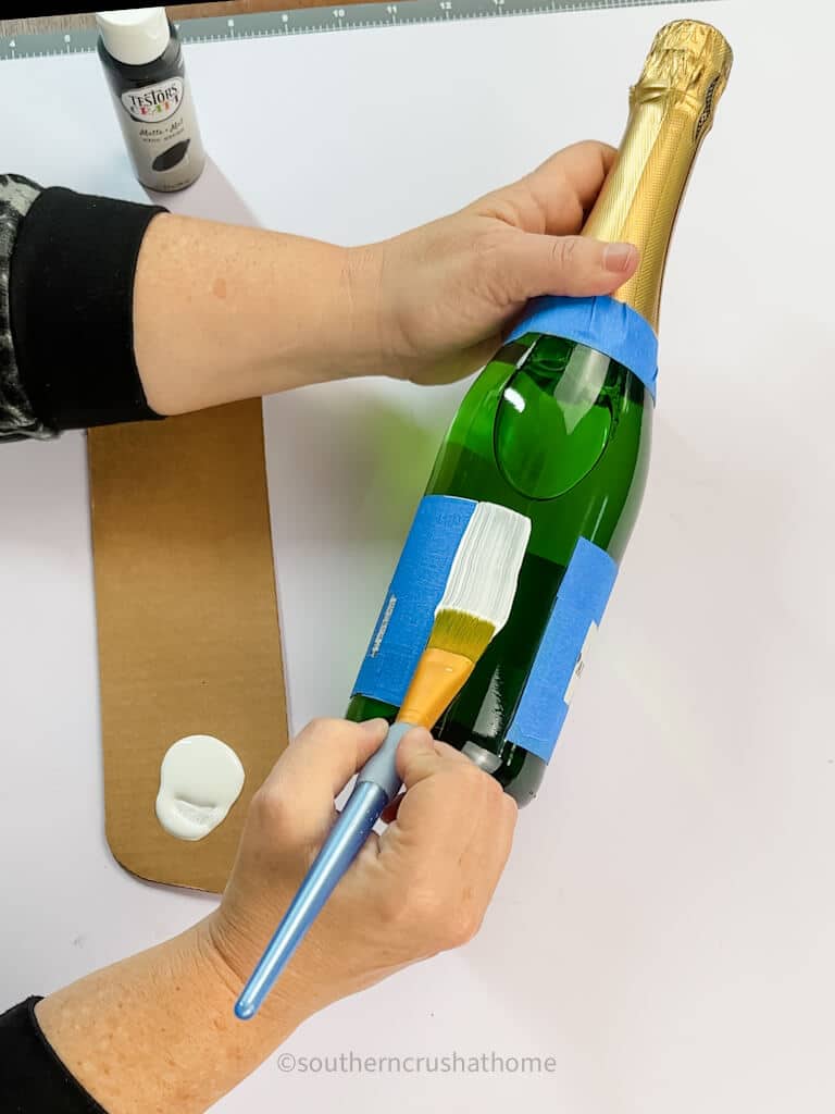 painting on white paint to champagne bottle
