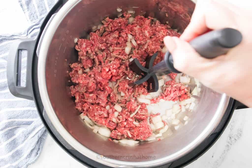 cooking hamburger meat and onions with tenderizer tool