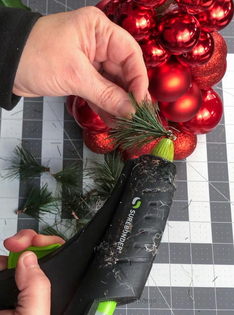 adding hot glue to greenery