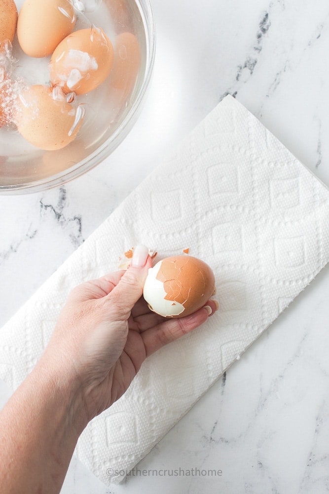 peeling brown shell from boiled egg