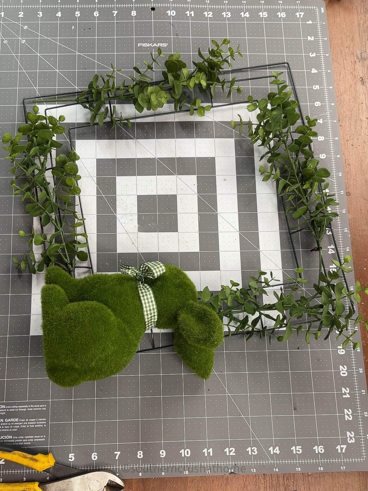adding greenery and bunny to wreath form